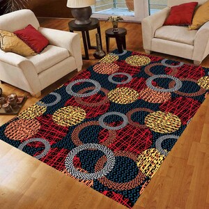 May include: A rectangular rug with a striking geometric design. It features large circles in yellow, orange, and grey, set against a red and black backdrop. The rug's pattern creates a modern, eye-catching look for a living space.