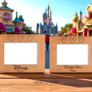 May include: Two wooden picture frames with Mickey Mouse and Minnie Mouse designs. The left frame has "Disney 2025" text, and the right frame has "Custom Your Text". The frames are on a wooden surface with a blurred theme park background.