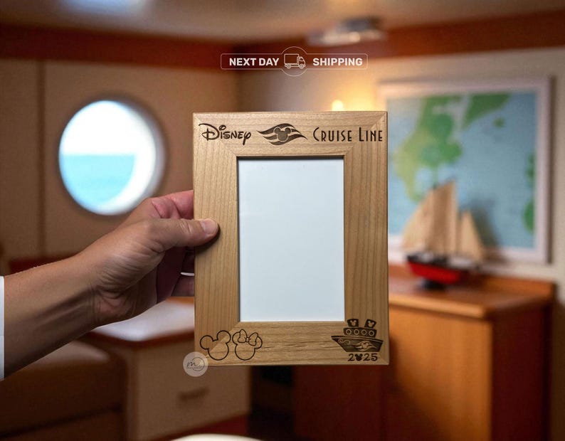 May include: A light-colored wooden picture frame with the words "Disney Cruise Line" and Mickey Mouse ears engraved on the frame. The frame has a rectangular opening for a photo and a small ship illustration.