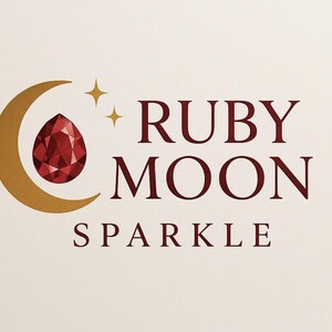 Pode incluir: Design de logotipo com uma gema de rubi em forma de gota, dentro de uma lua crescente dourada. Duas estrelas douradas acima do texto "RUBY MOON SPARKLE" em vermelho escuro, sobre fundo creme.