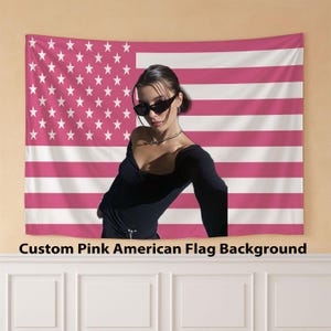 Puede incluir: Un tapiz rosa con la bandera americana, estrellas y rayas blancas. El texto "Custom Pink American Flag Background" está en la parte inferior. Una persona está frente a la bandera, vistiendo un top negro y gafas de sol.