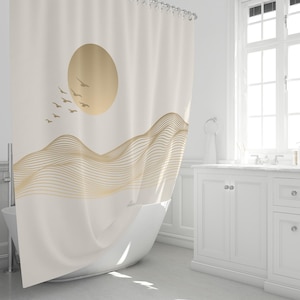 Puede incluir: Cortina de ducha color crema con un sol dorado, pájaros y un diseño de montañas onduladas. La cortina cuelga frente a una bañera blanca, creando una estética de baño serena y minimalista.