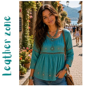 Peut inclure: Un haut bleu sarcelle à manches longues avec une encolure dégagée, des broderies complexes et un collier de perles décoratif avec un pendentif soleil central. Le vêtement présente un corsage ajusté avec une bande ajourée et un ourlet évasé.