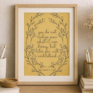 May include: A cozy workspace with a framed print featuring the text "you do not realize now what I am doing, but later you will understand." An alarm clock, coffee cup, and open notebook sit on a wooden desk, creating a warm, inviting atmosphere.