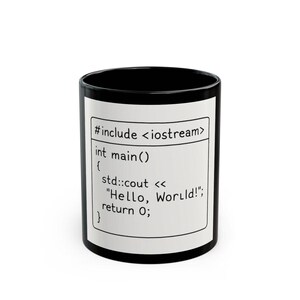 May include: Black coffee mug with a white panel displaying C++ code that prints "Hello, World!". The mug has a black interior and exterior rim. The text includes "#include <iostream>", "int main()", and "return 0;".