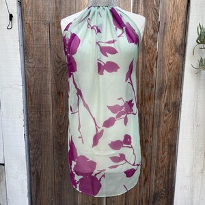 May include: A light green halter top with a purple floral print and a rhinestone choker.