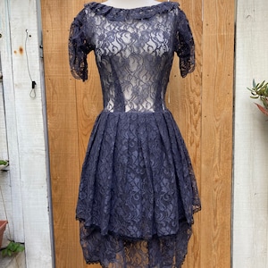 Sheer Grey lace short sleeve dress with ruffled hem boatneck and tired pleated skirt trimmed in black lace. SZ S