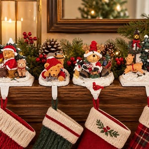 May include: A set of four decorative Christmas stocking holders featuring detailed figurines of teddy bears and Santa Claus on snowy bases. Each holder includes a metal hook for hanging stockings, with festive holiday scenes including trees and a lantern.