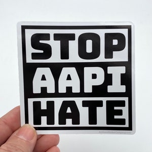 May include: Black and white sticker with the text "STOP AAPI HATE" in bold, white letters on a black background. The sticker is on a white background.