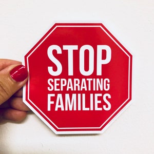 May include: Red octagonal stop sign with white text that reads "STOP SEPARATING FAMILIES".