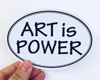 May include: White oval sticker with black text that reads "ART is POWER" and a website address at the bottom.