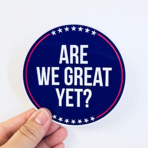 May include: A blue and red round sticker with white stars and the text "ARE WE GREAT YET?"