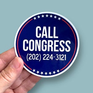 May include: A round sticker with a blue background and the words "CALL CONGRESS" in white. The sticker also includes the phone number (202) 224-3121 in white. A red and white border surrounds the text, and white stars are at the top.