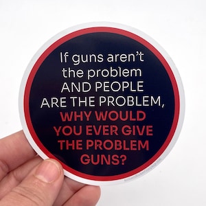 May include: A round sticker with a red border and a black background. The sticker has white text that reads: "If guns aren't the problem AND PEOPLE ARE THE PROBLEM, WHY WOULD YOU EVER GIVE THE PROBLEM GUNS?" The text is in a bold, sans-serif font.