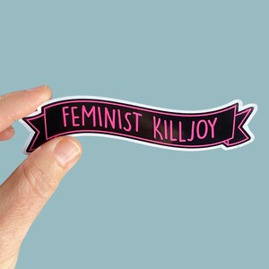 May include: Black and white banner with pink text that reads "Feminist Killjoy".