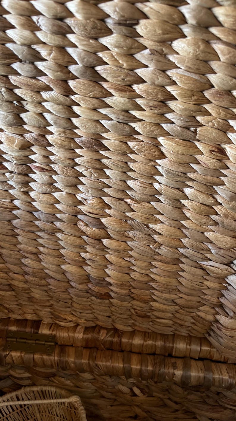 May include: Close-up of a woven basket texture. The basket is made of natural, light brown fibers, tightly woven in a repeating pattern. The texture is rough and organic, suggesting a handmade item.