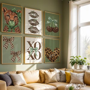 May include: A gallery wall set of six framed art prints featuring leopard print motifs, including a cheetah with a green bow, leopard lips, cherries, bows, the text XOXO with a green bow, and a leopard print heart on a sage green background.