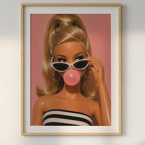 May include: A framed wall art print featuring a blonde doll with a high ponytail, wearing white cat-eye sunglasses and gold hoop earrings. The doll has a pink bubblegum bubble in front of its mouth and wears a black and white striped tube top.