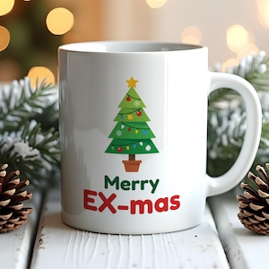 Op de afbeelding: Een witte keramische mok met een afbeelding van een groene kerstboom in een bruine pot, versierd met kleurrijke ornamenten en een gele ster. Onder de boom staat de tekst Merry EX-mas in groene en rode letters op de voorzijde.