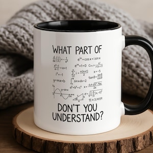 Könnte beinhalten: Ein weißer Keramikbecher mit schwarzem Innenraum und Henkel, bedruckt mit schwarzen mathematischen Formeln und dem Text "WHAT PART OF" oben sowie "DON'T YOU UNDERSTAND?" unten, der verschiedene Gleichungen aus Analysis und Geometrie zeigt.