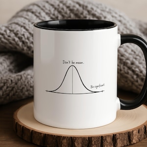 Peut inclure: Un mug en céramique blanc avec un intérieur et une anse noirs. L'extérieur présente un graphique en forme de courbe en cloche tracé en noir, avec le texte "Don't be mean." au-dessus du sommet et "Be significant." près de la courbe.