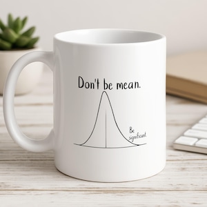 May include: A white ceramic mug featuring a black line drawing of a bell curve. The text "Don't be mean." is printed above the curve, and the text "Be significant." is printed to the right of the curve, near the base of the bell shape.