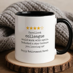Könnte beinhalten: Weiße Keramik-Tasse mit schwarzem Innenraum und Henkel. Auf der Tasse steht der Text "Excellent colleague would work with again. Deducted a star because you leaving us! Happy Retirement Sarah."