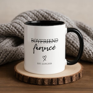 White mug with black handle featuring "BOYFRIEND" struck through, "fiancé", a heart, and "EST. 12.09.2026".