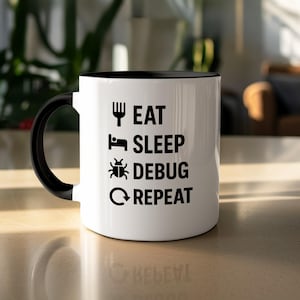 Pode incluir: Caneca de cerâmica branca com interior e alça pretos. A caneca apresenta as palavras "EAT SLEEP DEBUG REPEAT" em preto, juntamente com ícones de garfo, cama, inseto e seta circular.