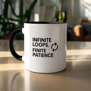 Può includere: Tazza in ceramica bianca con interno e manico neri. La tazza presenta il testo "INFINITE LOOPS, FINITE PATIENCE" in nero, insieme a un simbolo di freccia circolare. La tazza è su una superficie chiara.