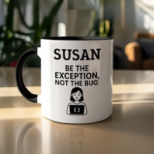 May include: White ceramic mug with a black interior and handle. The mug features the name "SUSAN" in bold black letters, along with the phrase "BE THE EXCEPTION, NOT THE BUG." Below the text is a graphic of a person holding a laptop.