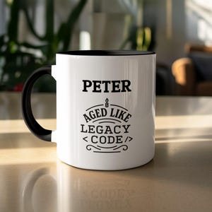 May include: White ceramic mug with a black interior and handle. The mug features the name "PETER" in bold black letters, along with the phrase "AGED LIKE LEGACY CODE" in a decorative font. A candle graphic is above the phrase.