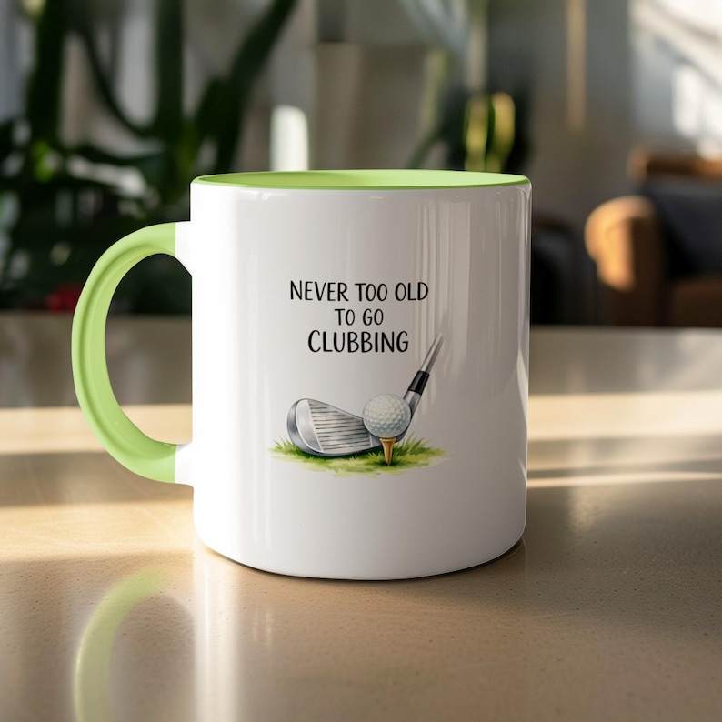 White mug with green handle, golf club, ball, and text "Never too old to go clubbing."