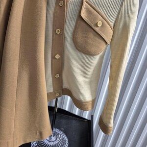 A vintage two-piece outfit in cream and tan. The top is a cream button-down shirt jacket style with contrasting tan pocket and a wide 60s collar. The skirt is a solid tan color. The outfit is displayed on a mannequin.