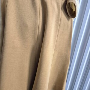 A tan-colored gored skirt with vertical seams and a coordinating tan and cream colored top. The skirt is made of a smooth soft double-knit wool blend fabric.