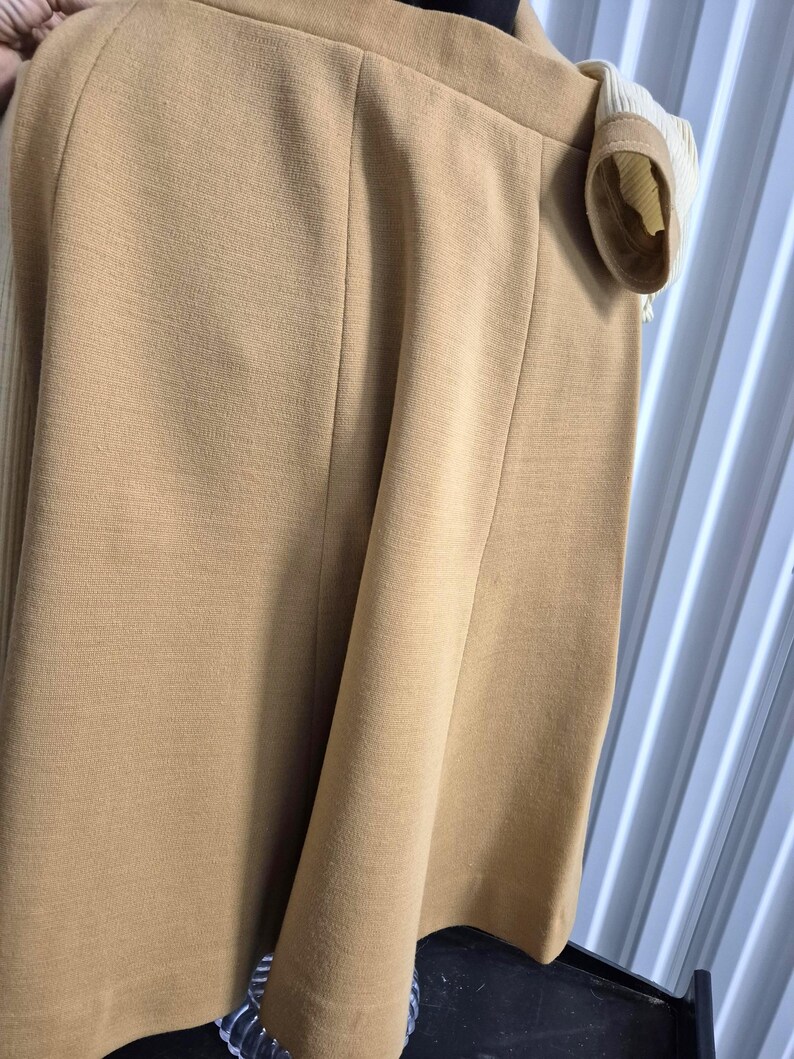 A tan-colored gored skirt with vertical seams and a coordinating tan and cream colored top. The skirt is made of a smooth soft double-knit wool blend fabric.