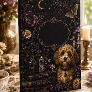 May include: A rectangular hardcover journal with a black cover featuring a golden crescent moon, a moth, purple flowers, mushrooms, stacked books, a crystal, a pocket watch, and a portrait of a fluffy brown dog with a collar and moon charm.