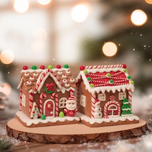 May include: Two gingerbread houses with red and white icing, decorated with candy canes, Santa, and a snowman. The houses sit on a wooden base, with a blurred background of Christmas lights and pine cones.