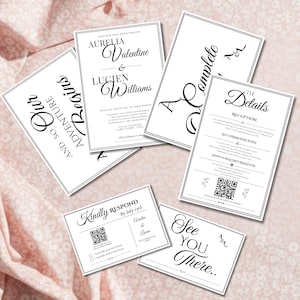 Könnte beinhalten: Eine Sammlung weißer Hochzeitseinladungskarten mit schwarzem Text. Die Karten enthalten Details, RSVP-Informationen und die Namen Aurelia und Lucien. Die Karten sind auf einem rosa Stoffhintergrund angeordnet.