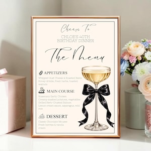 May include: A rectangular menu sign in a gold frame featuring the text Cheers To CHLOE'S 40TH BIRTHDAY DINNER The Menu, with sections for Appetizers, Main Course, and Dessert, and an illustration of a champagne coupe glass with a black bow.
