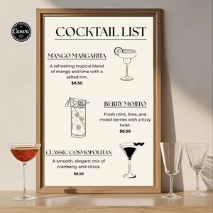 Könnte beinhalten: Ein gerahmtes Cocktail-Menü mit Mango Margarita, Berry Mojito und Classic Cosmopolitan. Die Liste enthält Illustrationen jedes Cocktails und deren Beschreibungen. Rechts stehen zwei leere Weingläser, links ein Cocktailglas mit einem roten Getränk.