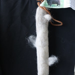 May include: A white wool roving wrapped in a brown twine with a tag that reads "A WOOLLY GIFT is a warm and cozy feeling from quality fleece.  Our fleeces are hand-processed to bring you the softest, most luxurious hairs to make your home and cozy, even in the tree and your wool will be a treasure. Trillium Valley Farm"