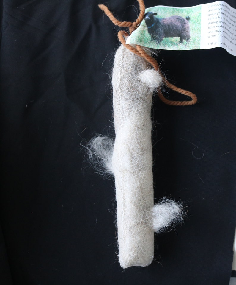 K&ouml;nnte beinhalten: Ein wei&szlig;er Wollrohling, umwickelt mit braunem Garn, mit einem Etikett, auf dem steht: "A WOOLLY GIFT is a warm and cozy feeling from quality fleece.  Our fleeces are hand-processed to bring you the softest, most luxurious hairs to make your home and cozy, even in the tree and your wool will be a treasure. Trillium Valley Farm"