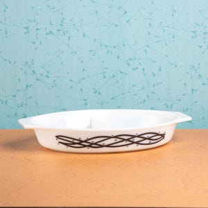 May include: A white ceramic mug with a black handle and the text "But First, Coffee" in a bold, black font. The mug is set against a blurred background, suggesting a cozy setting.