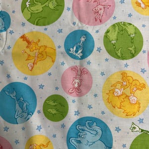May include: White fabric with a pattern of colorful circles containing cartoon characters and blue stars. The circles are in shades of pink, yellow, green, and blue. The cartoon characters are in various poses.
