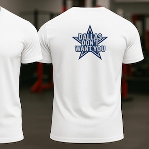 Puede incluir: Camiseta blanca con cuello redondo. La parte delantera presenta un óvalo azul marino con el número "214". La parte trasera muestra una estrella azul marino con el texto "DALLAS DON'T WANT YOU".