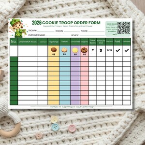 May include: A white and green cookie order form with the text "2026 COOKIE TROOP ORDER FORM". The form includes sections for customer information, cookie types, and order details. A QR code is in the upper right corner.