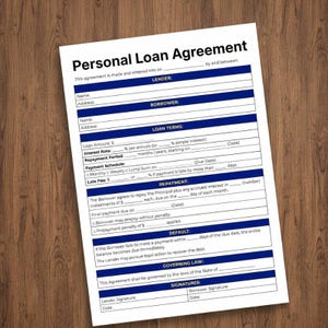 May include: A white Personal Loan Agreement form with blue text and borders. The document includes sections for lender and borrower information, loan terms, repayment details, and signatures. The agreement is on a wooden surface.