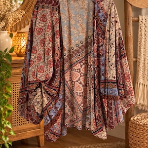 May include: A lightweight open-front kimono featuring a patchwork design with various floral and geometric patterns in shades of burgundy, light blue, cream, and dark brown. The garment has wide, loose sleeves and a relaxed, flowing silhouette.