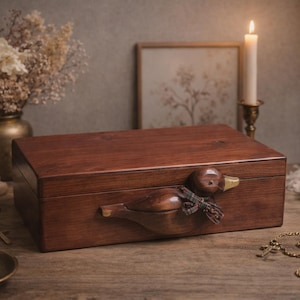 May include: A rectangular wooden box with a duck-shaped handle. The box is a rich, dark brown colour and sits on a wooden surface. A small, decorative scarf is tied around the duck's neck. The scene is lit by a candle, creating a warm, inviting atmosphere.